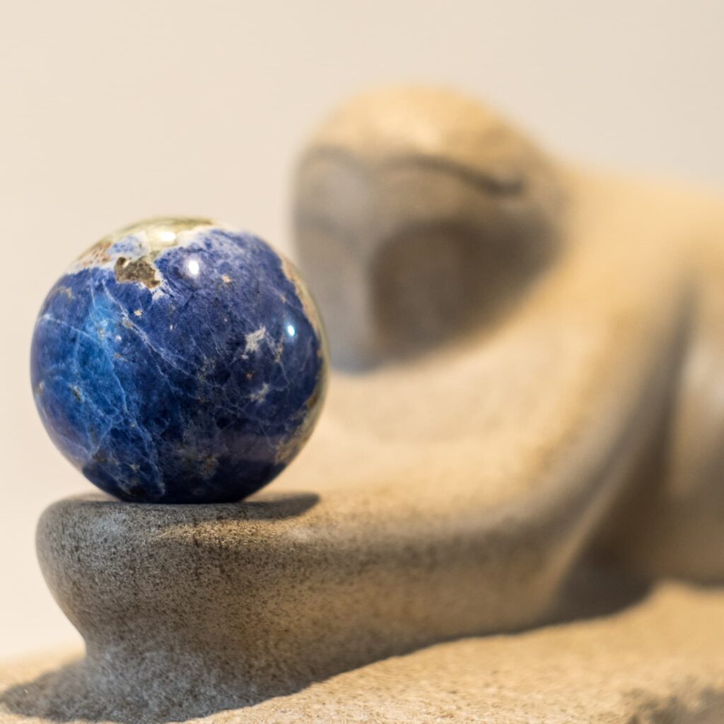 Limestone sculpture called "The Gift" carved in Indiana limestone in 2016 and including a Lapis Lazuli sphere. Frontal right view with focus on the sphere.